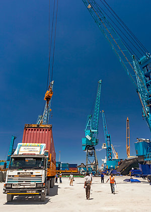 A cargo ship picking up a load from a truck trailer, in Mombasa port, Kenya. 