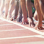 Runners poised at starting blocks on track.
