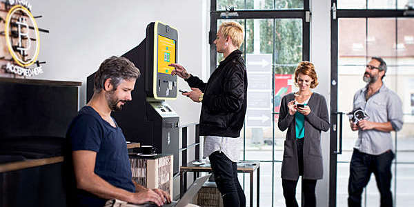 People standing at a Bitcoin ATM to buy cryptocurrencies.